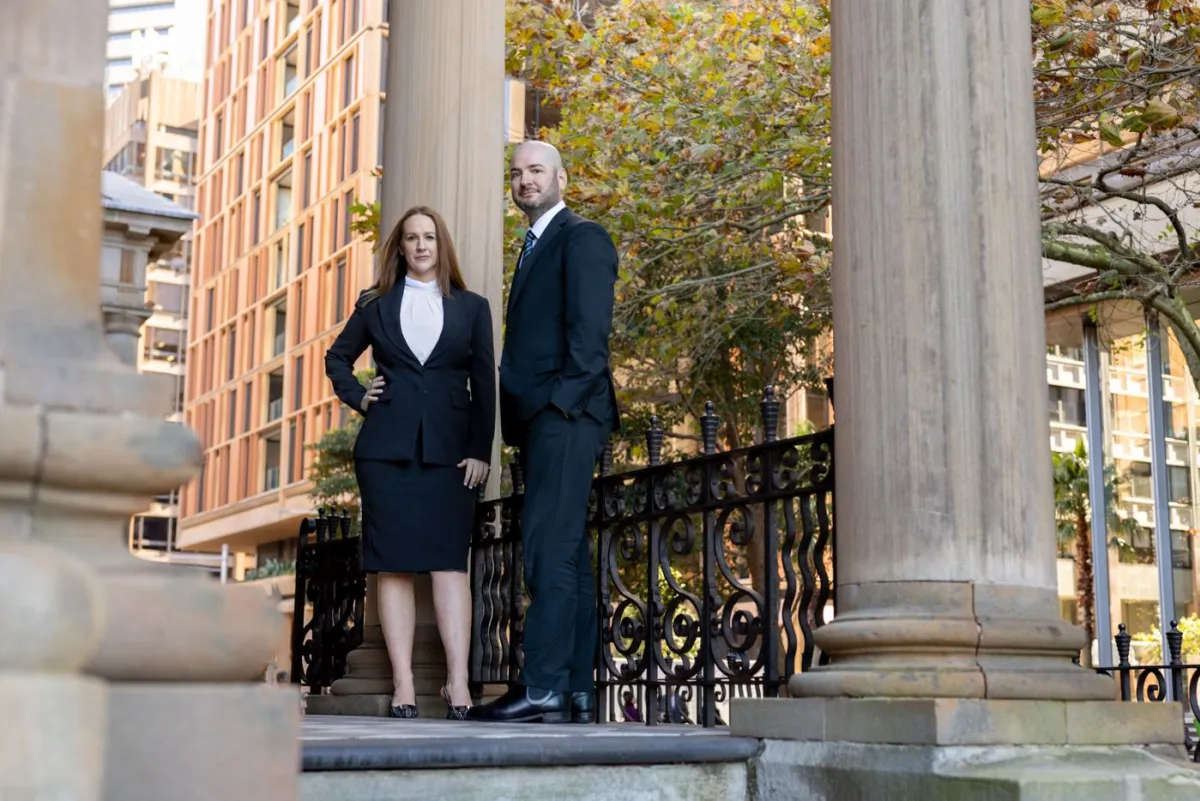 Two lawyers standing on a building colonnade.